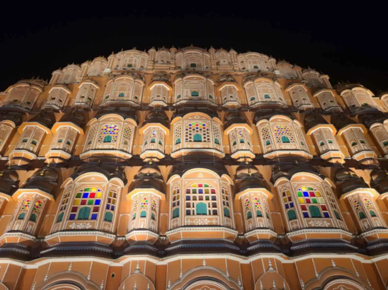The honeycomb sandstone façade of Hawa Mahal lit up at dusk